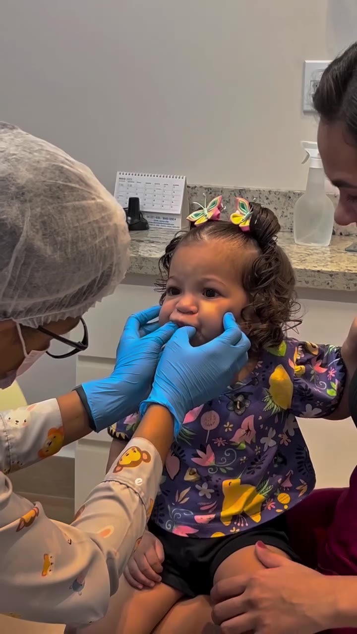 Bebê sendo atendido no colo por odontopediatra da COS